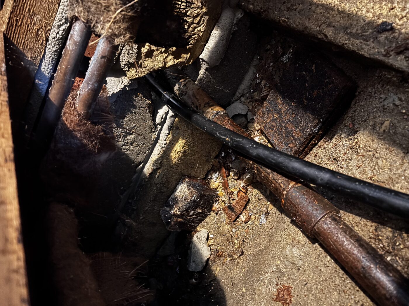 Old corroded pipework in the rubble void — decades of age visible