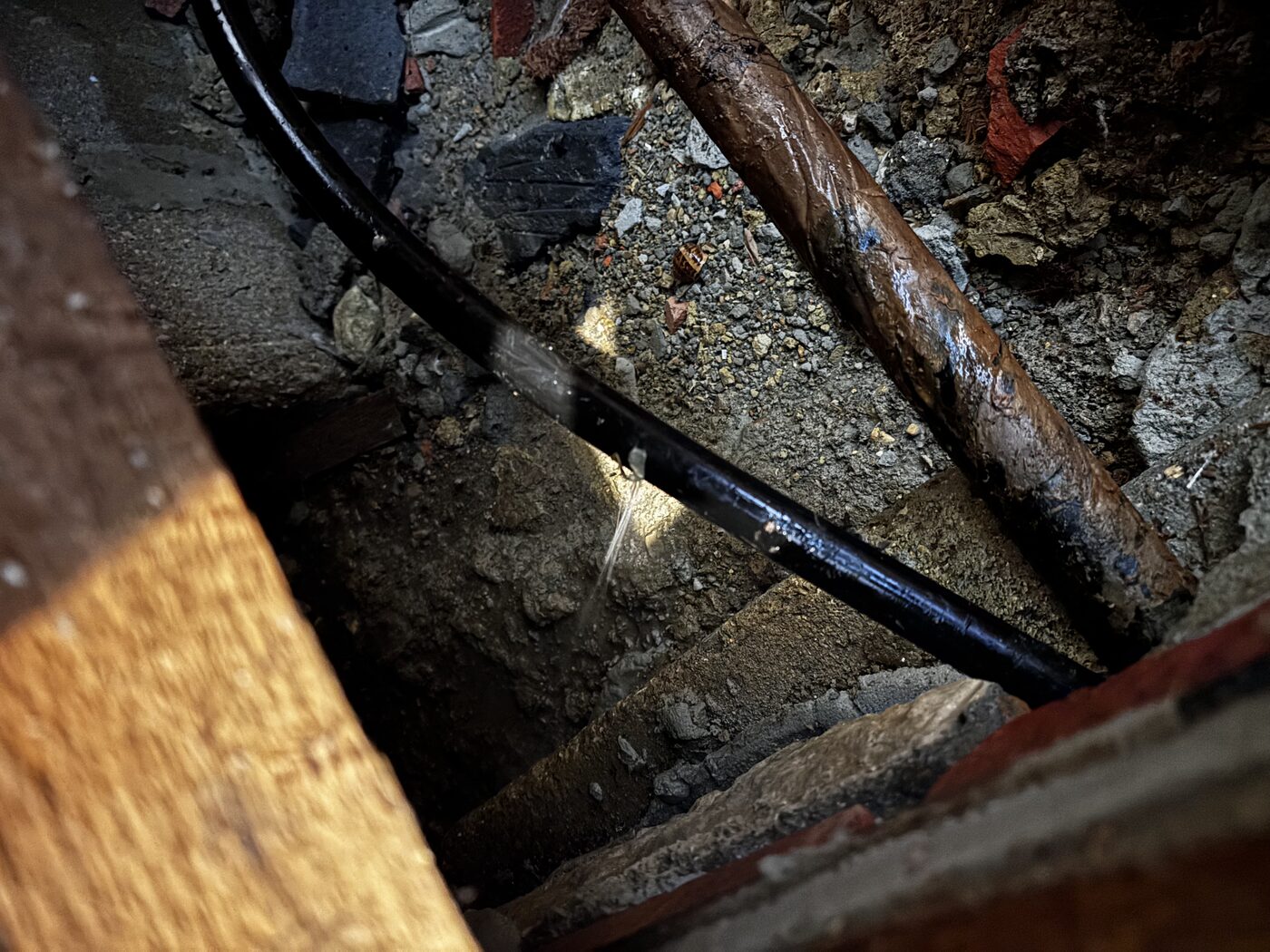 Leak found — water jetting from a joint on the service pipe beneath the boards