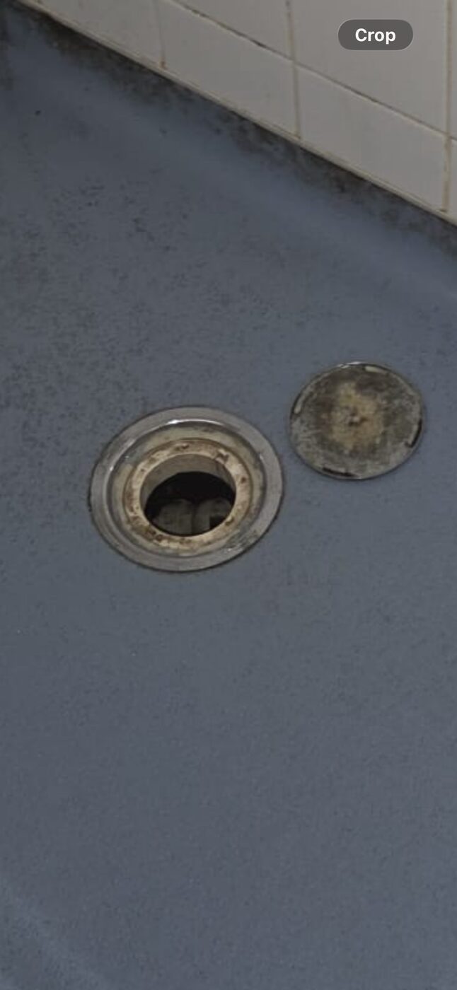 Collapsed wetroom waste — cover removed, drain body corroded and failed, no underfloor access