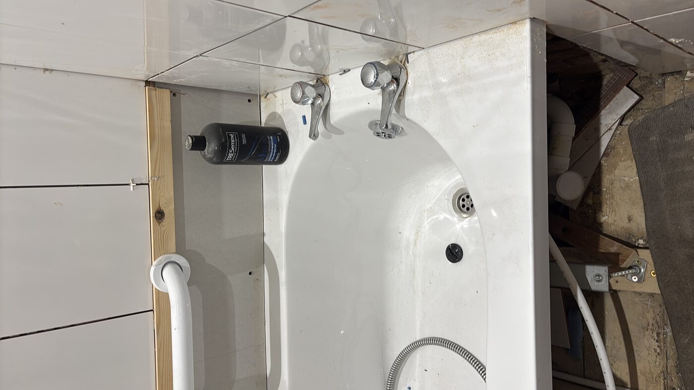 Bath with side panel removed — leak suspected underneath