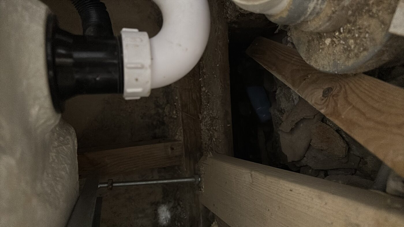 Underfloor void — waste pipe and structural timbers visible