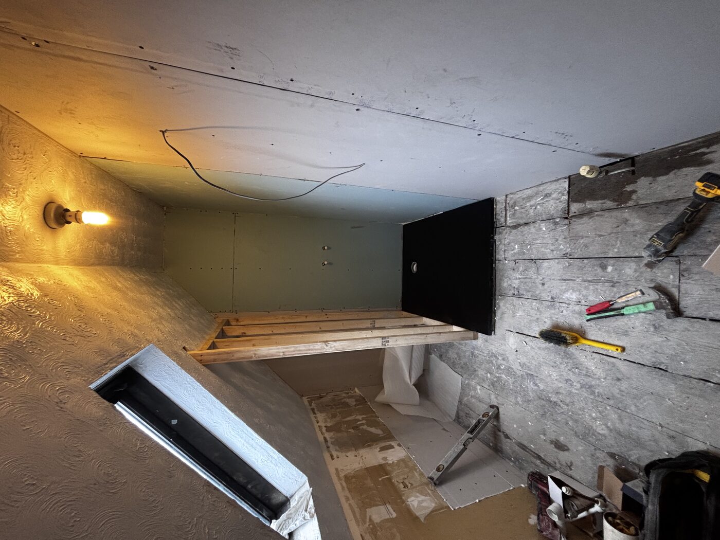 Strip-out complete — stud wall being built, black shower tray positioned, aqua panels going up