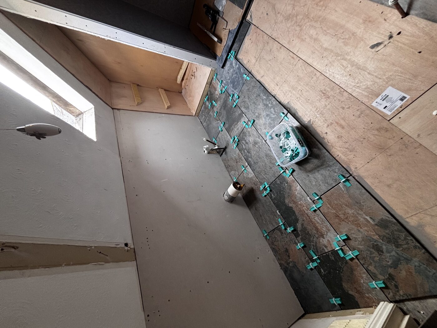 Floor tiles laid with levelling clips — large format slate-effect across the full room