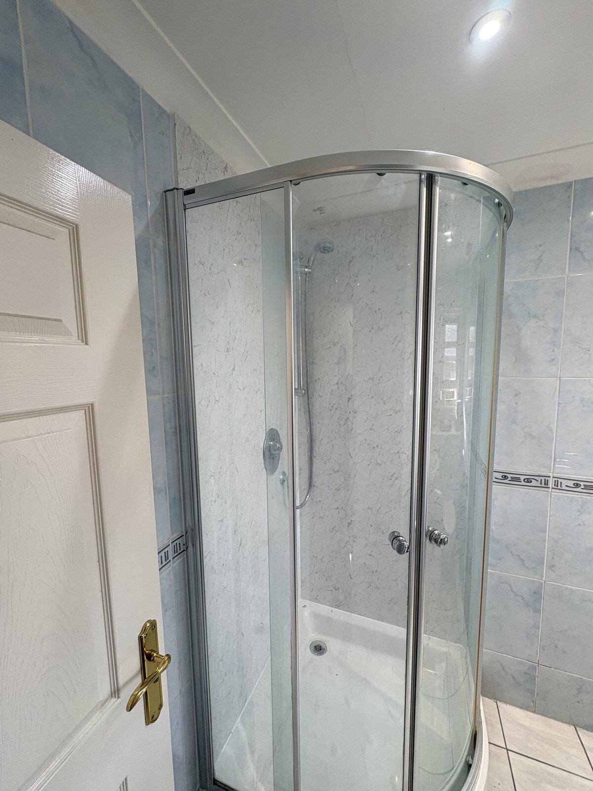 Completed marble-effect wall panels behind the retained shower enclosure