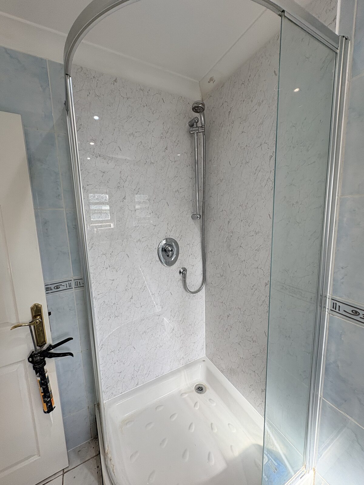 Finished marble-effect shower panels with the existing enclosure retained, viewed with the door open