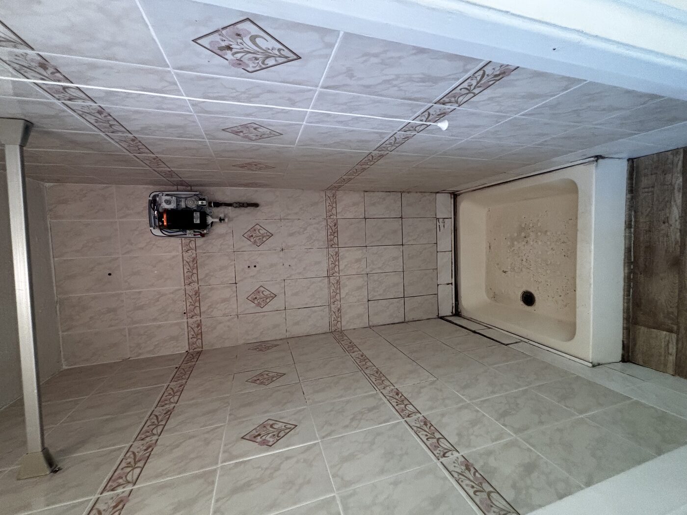 Original shower — dated tiles, old tray, and a leak that had been going undetected