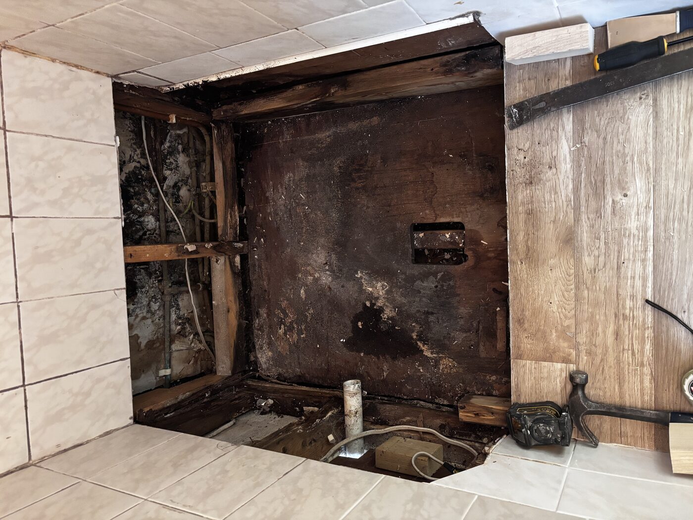 Tray lifted — years of undetected leaking had rotted the subfloor timbers completely
